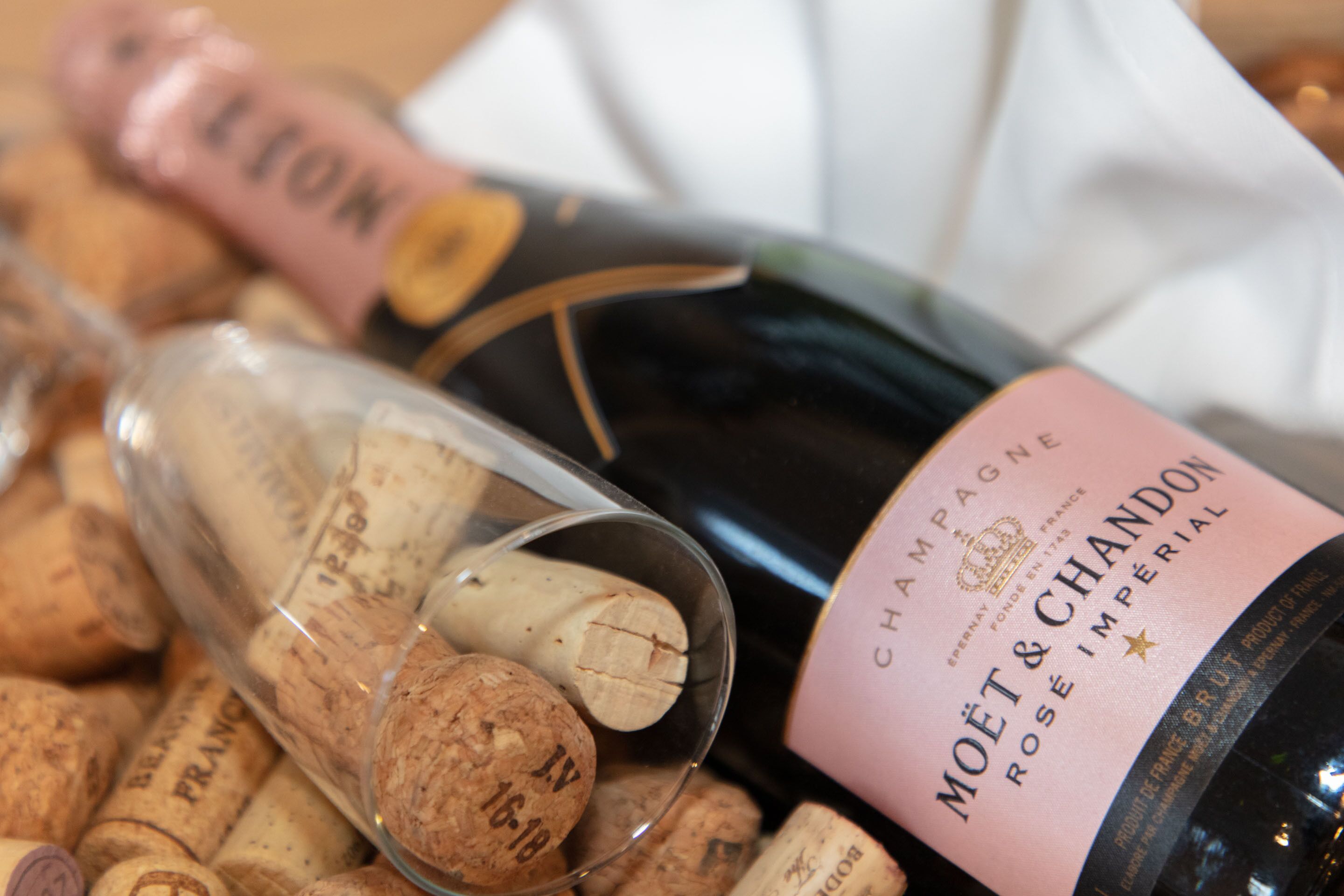 A bottle of Moët & Chandon champagne with a pink label, surrounded by wine corks.