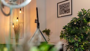 Un intérieur moderne au design minimaliste, agrémenté d’un luminaire suspendu, d’une photographie encadrée au mur et d’une plante en pot.