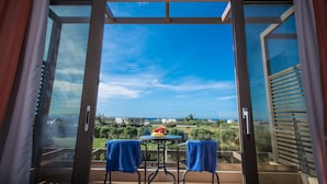 Un balcon avec une table et des chaises, une vue sur la mer et un ciel dégagé.