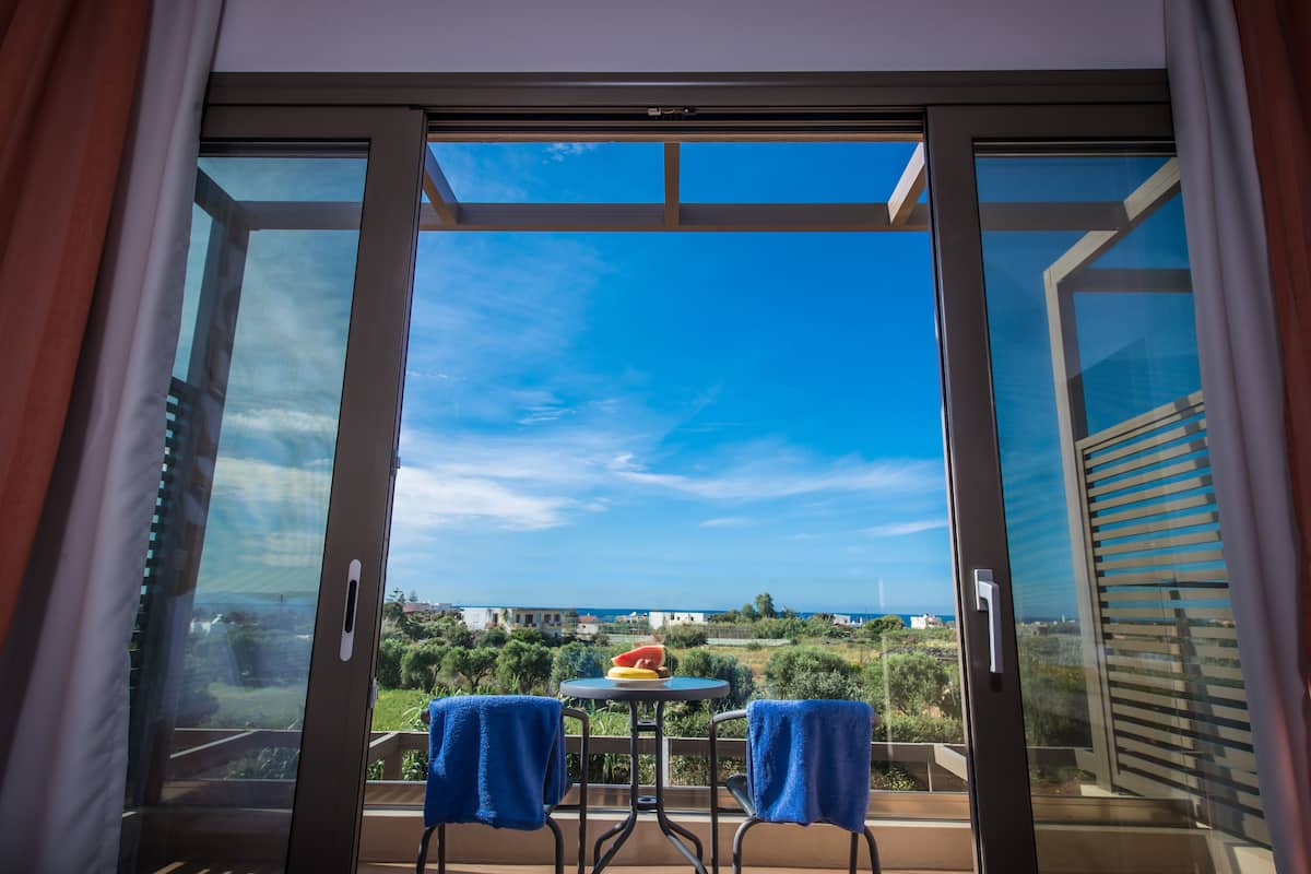 Un balcón con mesa y sillas, vista al mar y cielo despejado.