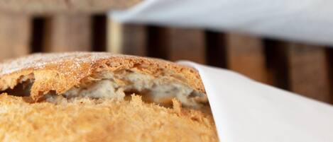 A loaf of bread with a crusty exterior and a soft interior, partially wrapped in white paper.