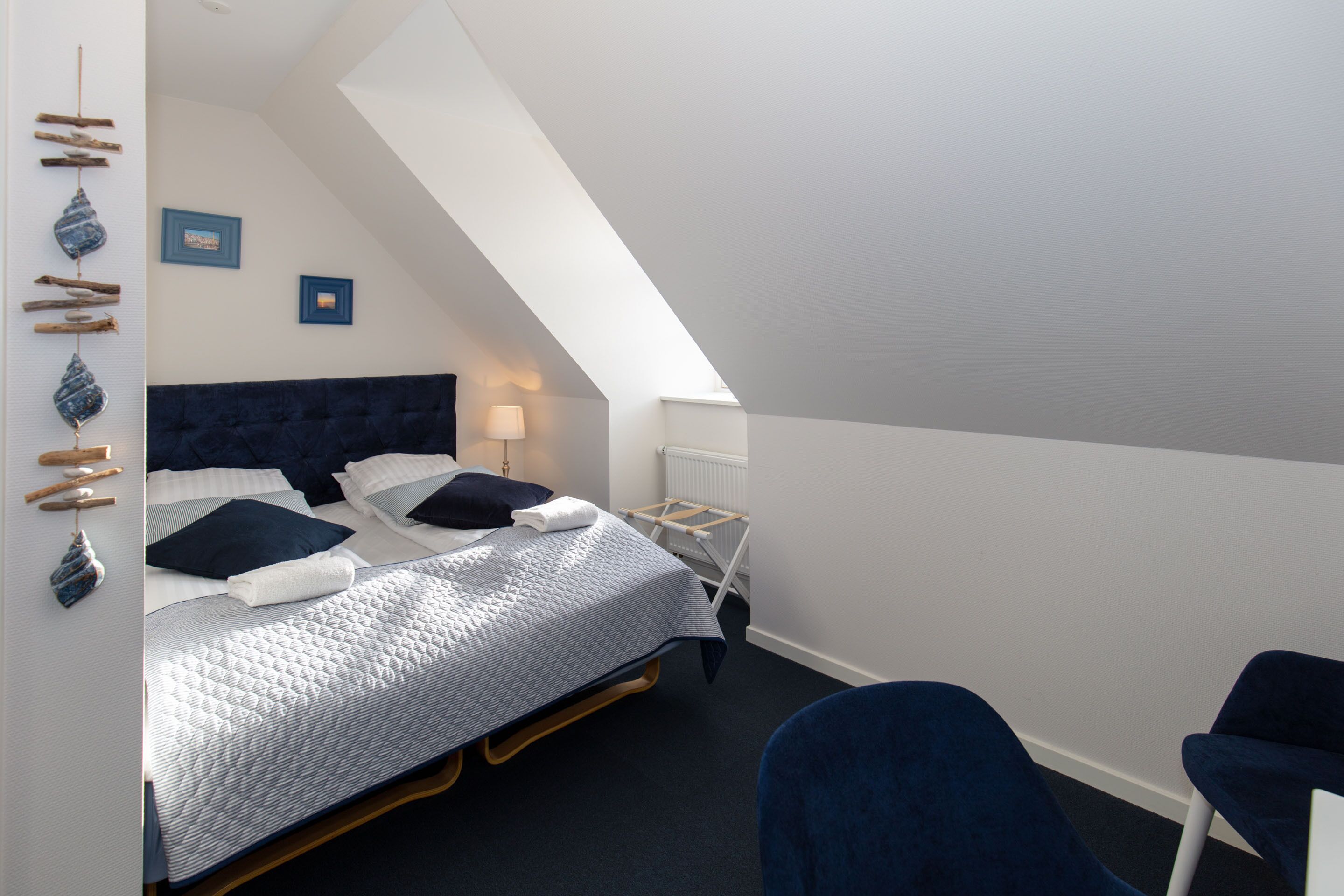 A bedroom with a bed, two bedside tables, a chair, and a radiator.