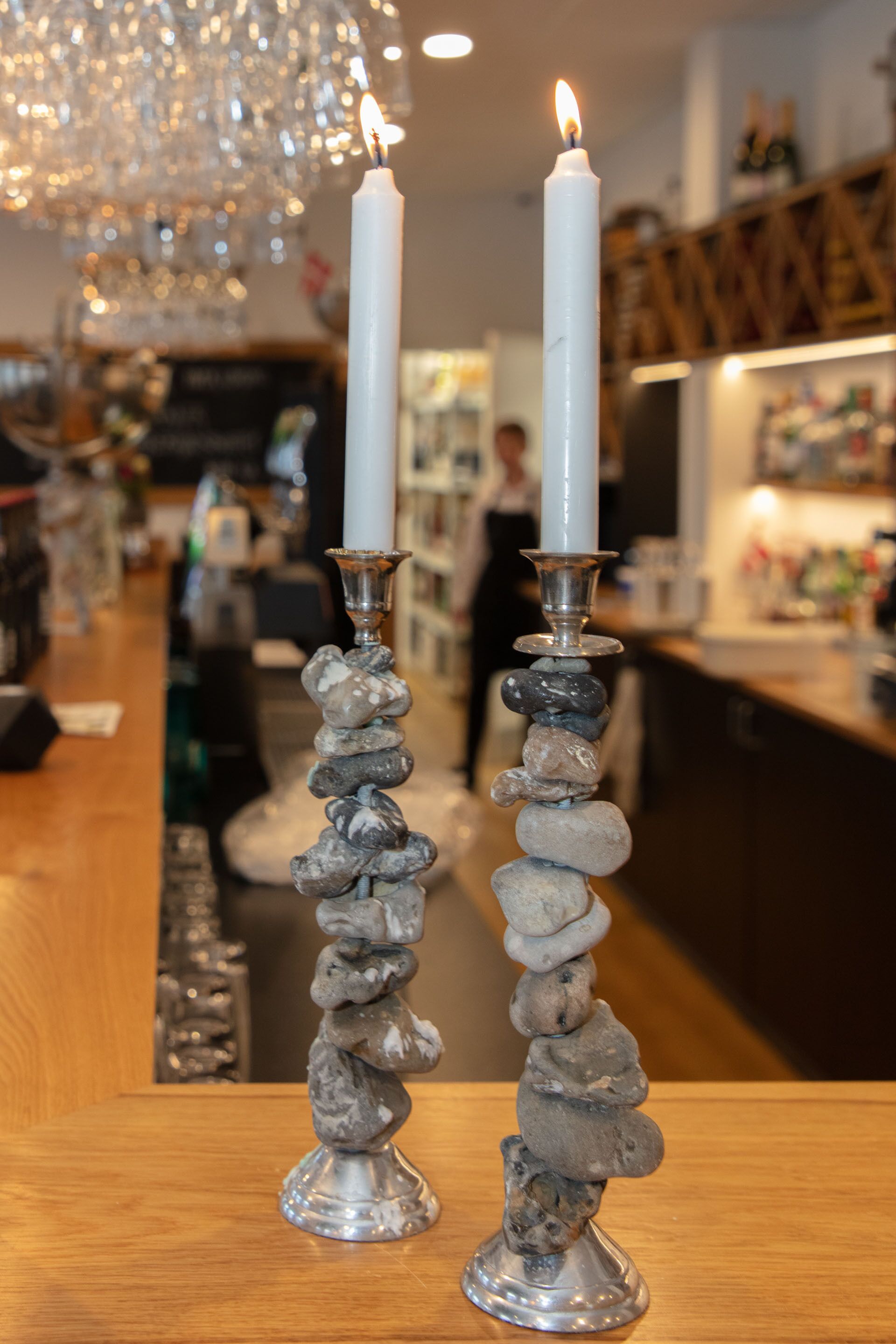 Dos velas blancas sobre pedestales de piedra en un bar.