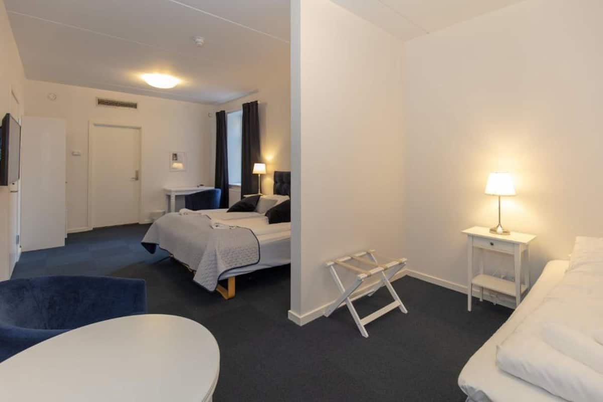 Habitación de hotel con cama, escritorio, silla y una mesita.