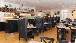A restaurant with a bar area, multiple dining tables, and booths.