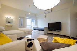 A modern hotel room with a large bed, a sofa, a TV, and a circular ceiling light.