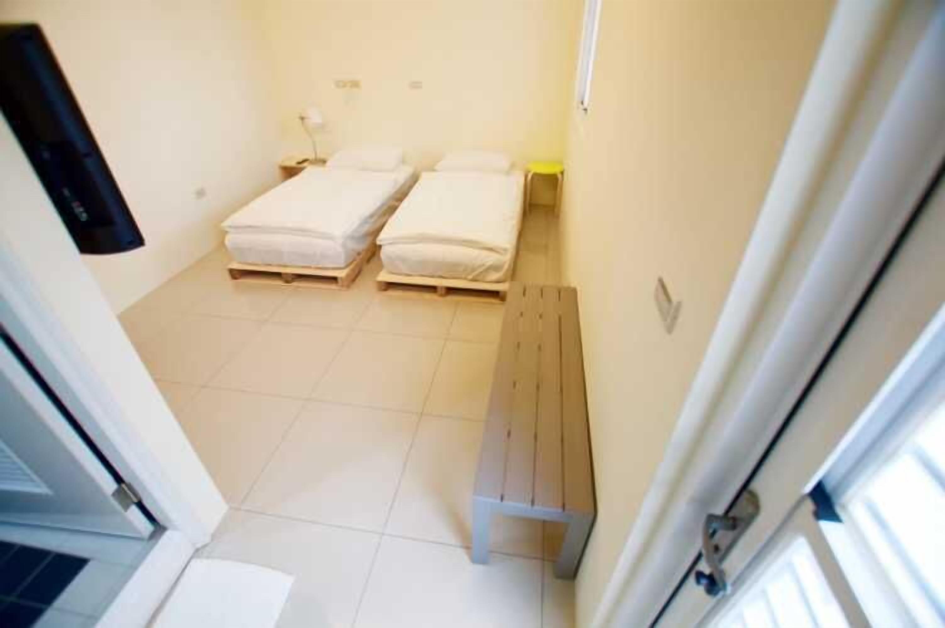 A small, narrow room with two single beds and a bench.