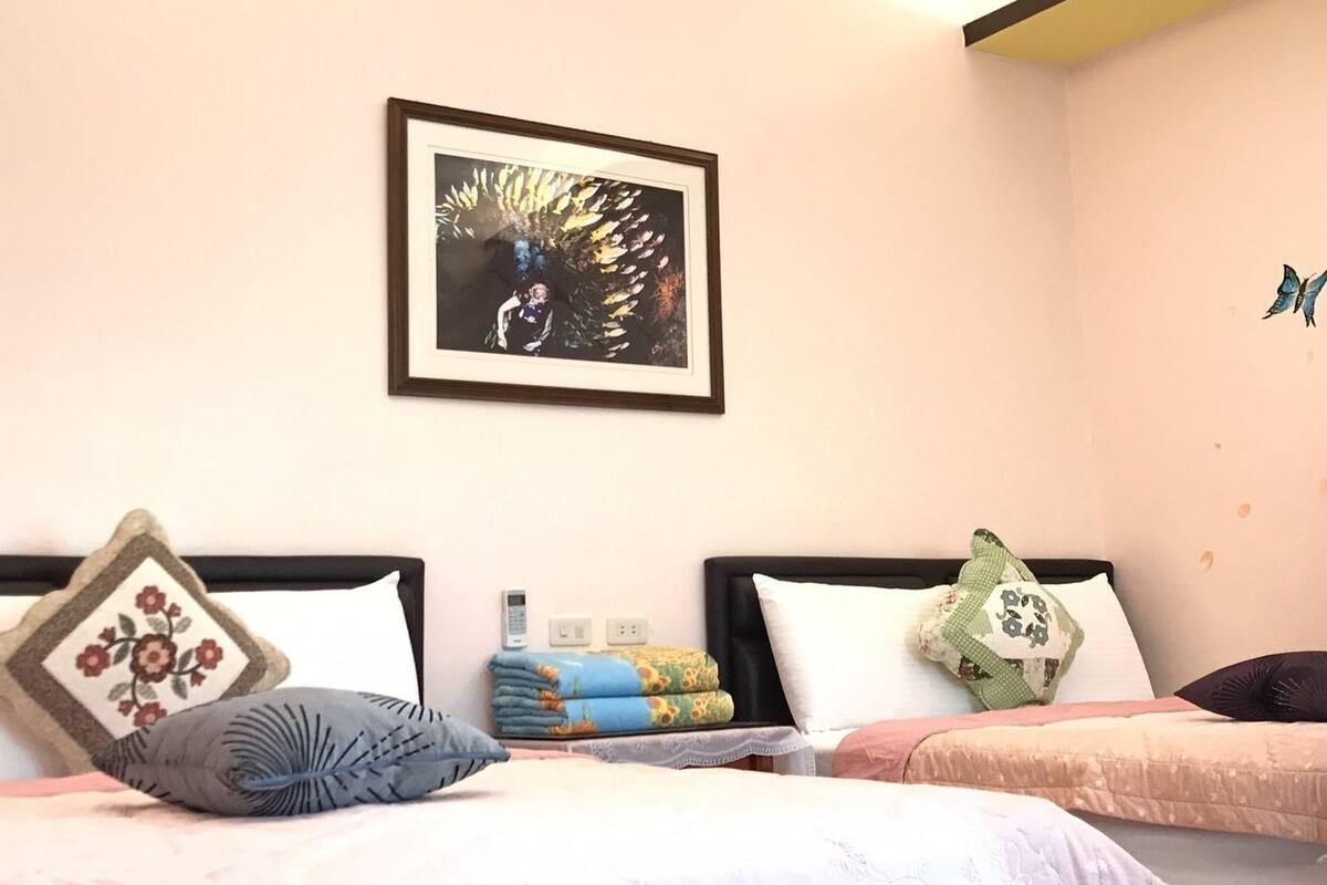 Un dormitorio con dos camas, una obra de arte enmarcada en la pared y una pequeña mariposa decorativa en la pared.