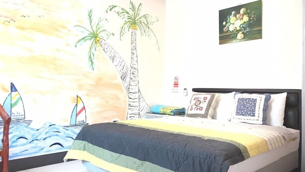 Un dormitorio con cama, un mural en la pared, un cuadro y una mesita.