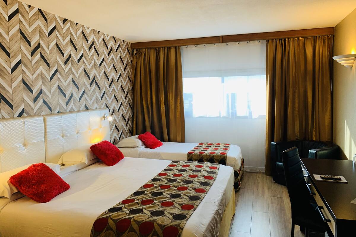 Een hotelkamer met twee bedden, een bureau en een stoel.