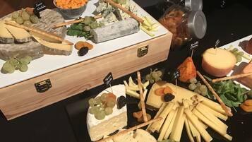 A cheese and fruit platter with various cheeses, grapes, and crackers.