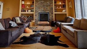 A cozy living room with two sofas, a fireplace, bookshelves, and a stone accent wall. - Hotel Horizon (Sutton)