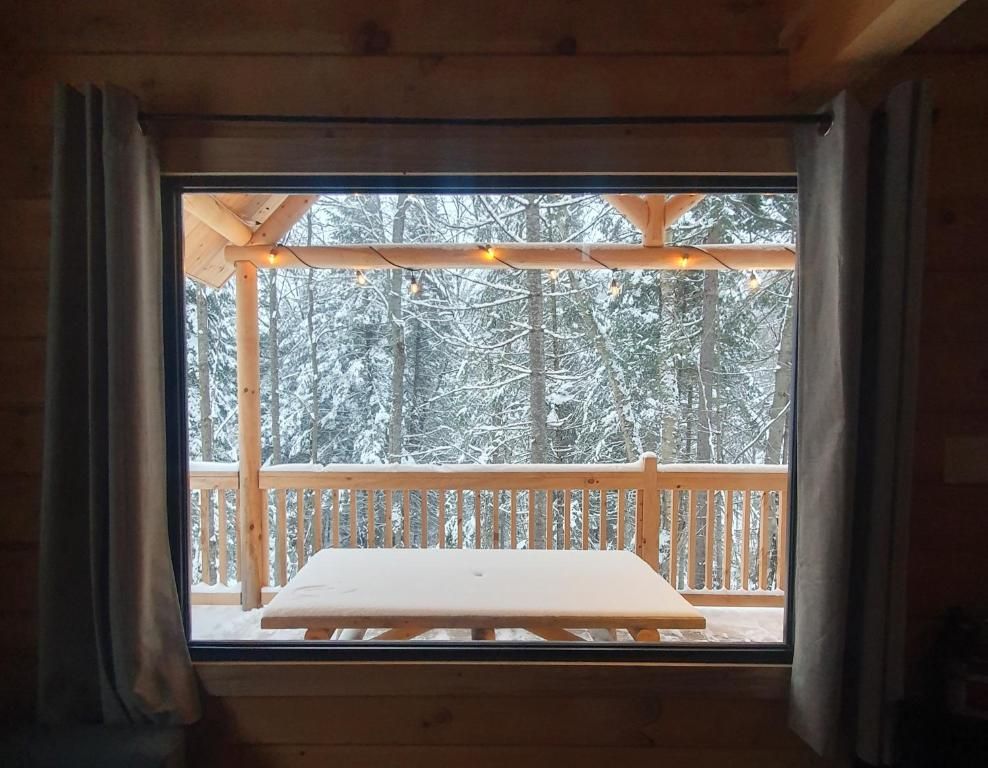 A wooden cabin with a window overlooking a snowy forest.