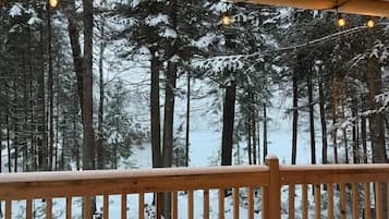 Un banco de madera en un balcón con vistas a un bosque nevado.