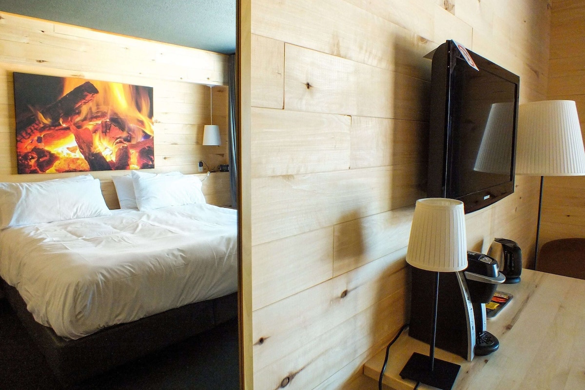 Une chambre d’hôtel équipée d’un lit, d’un téléviseur fixé au mur et d’une machine à café.