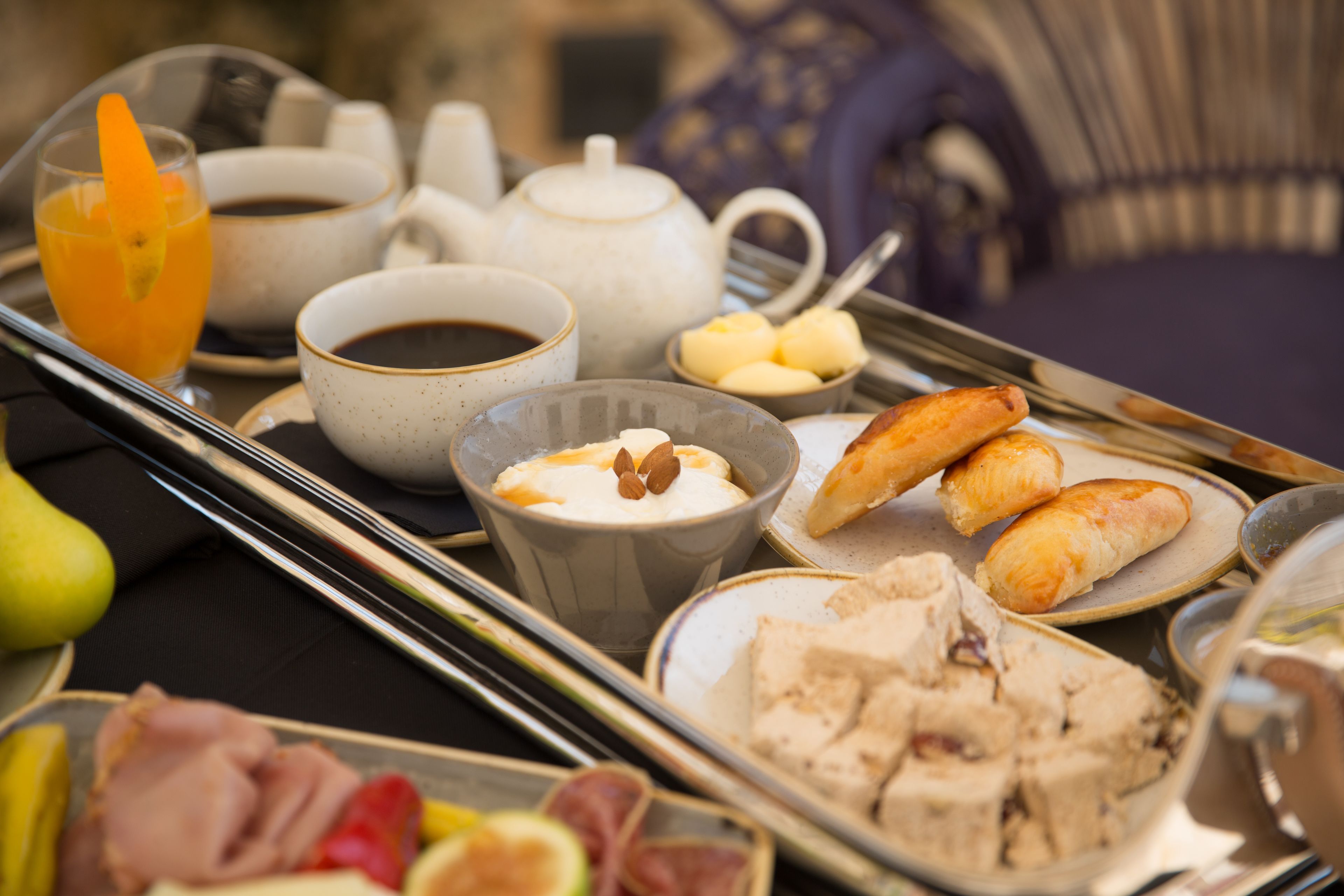 A breakfast tray with various food items, including pastries, fruit, and beverages.