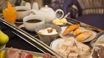 A breakfast tray with various food items, including pastries, fruit, and beverages.