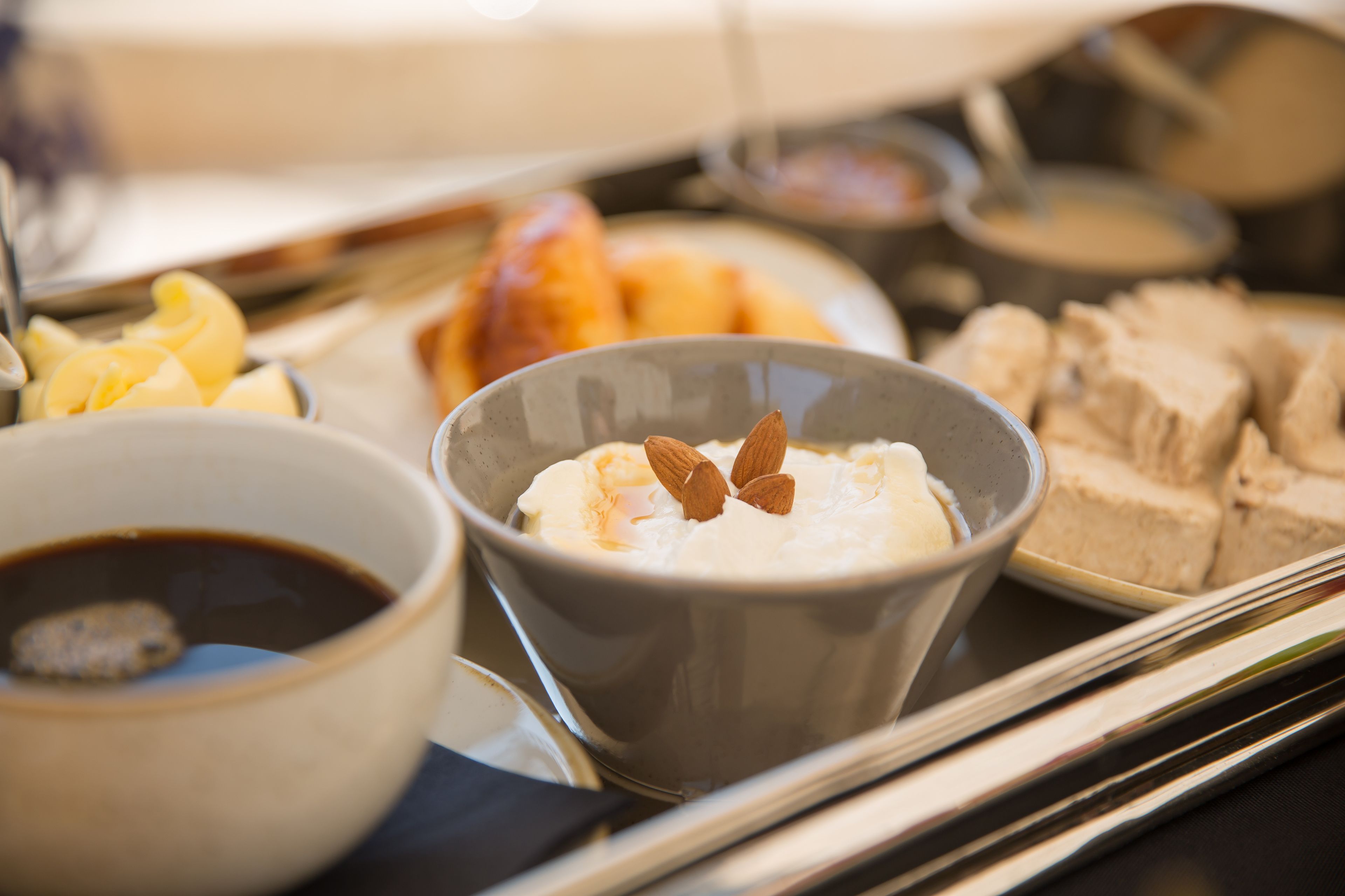 A tray with a bowl of soup, a bowl of coffee, and some pastries.