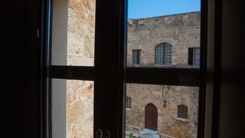 A view through a window of a stone building with arched windows and a door.