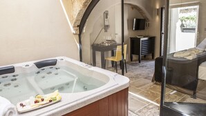 Egy wellnesszóna, amelyben található egy jakuzzi, egy poharakkal megterített asztal és egy szék.