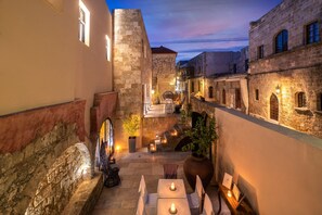 A narrow alleyway with stone buildings, outdoor seating, and a staircase leading to a higher level. - Allegory Boutique Hotel (Rhodes)