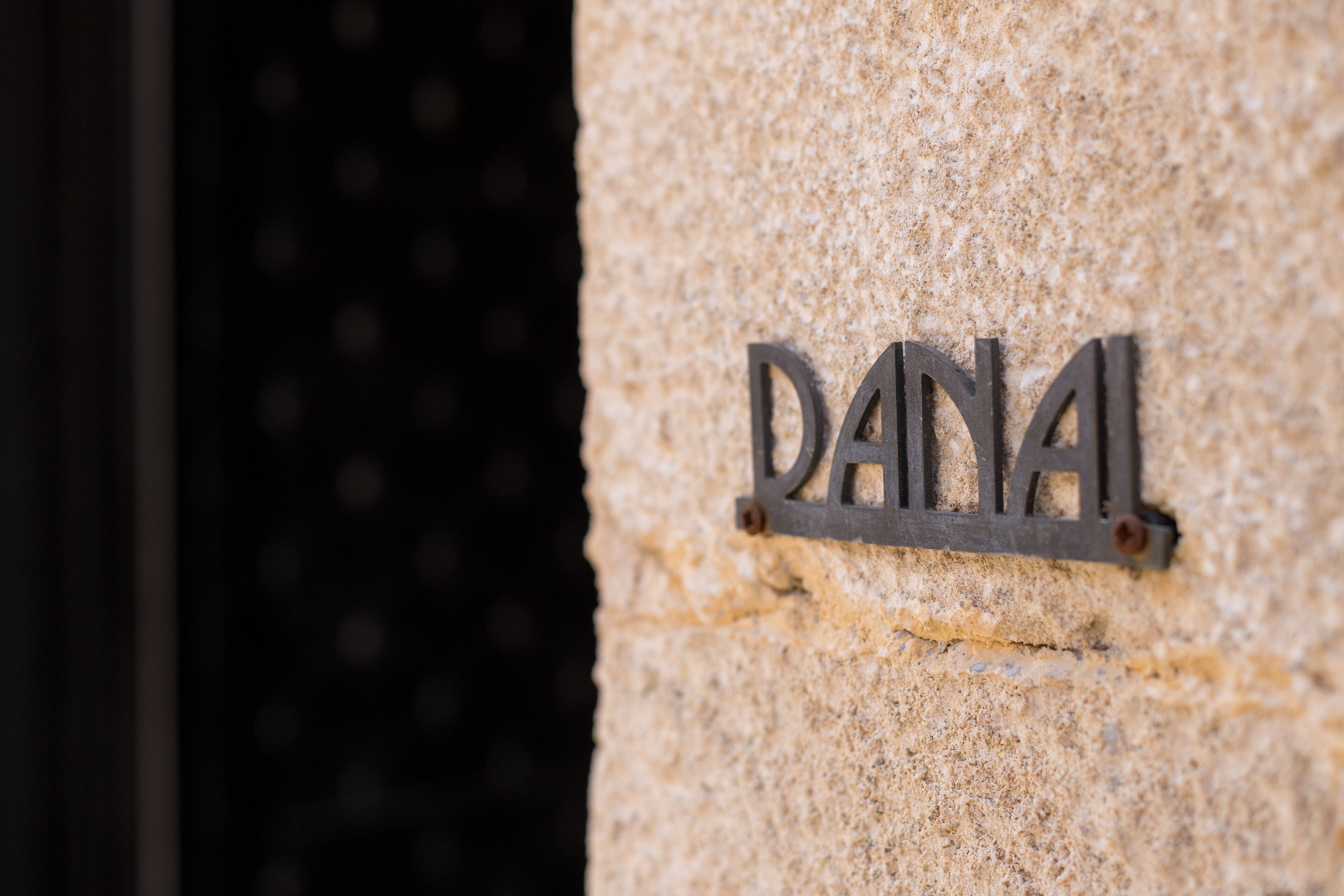 Un muro de piedra con una placa metálica que dice "DANAL".