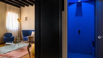 Ein modernes Wohnzimmer mit einem blauen Sessel, einem Glastisch und einem Holznachttisch.