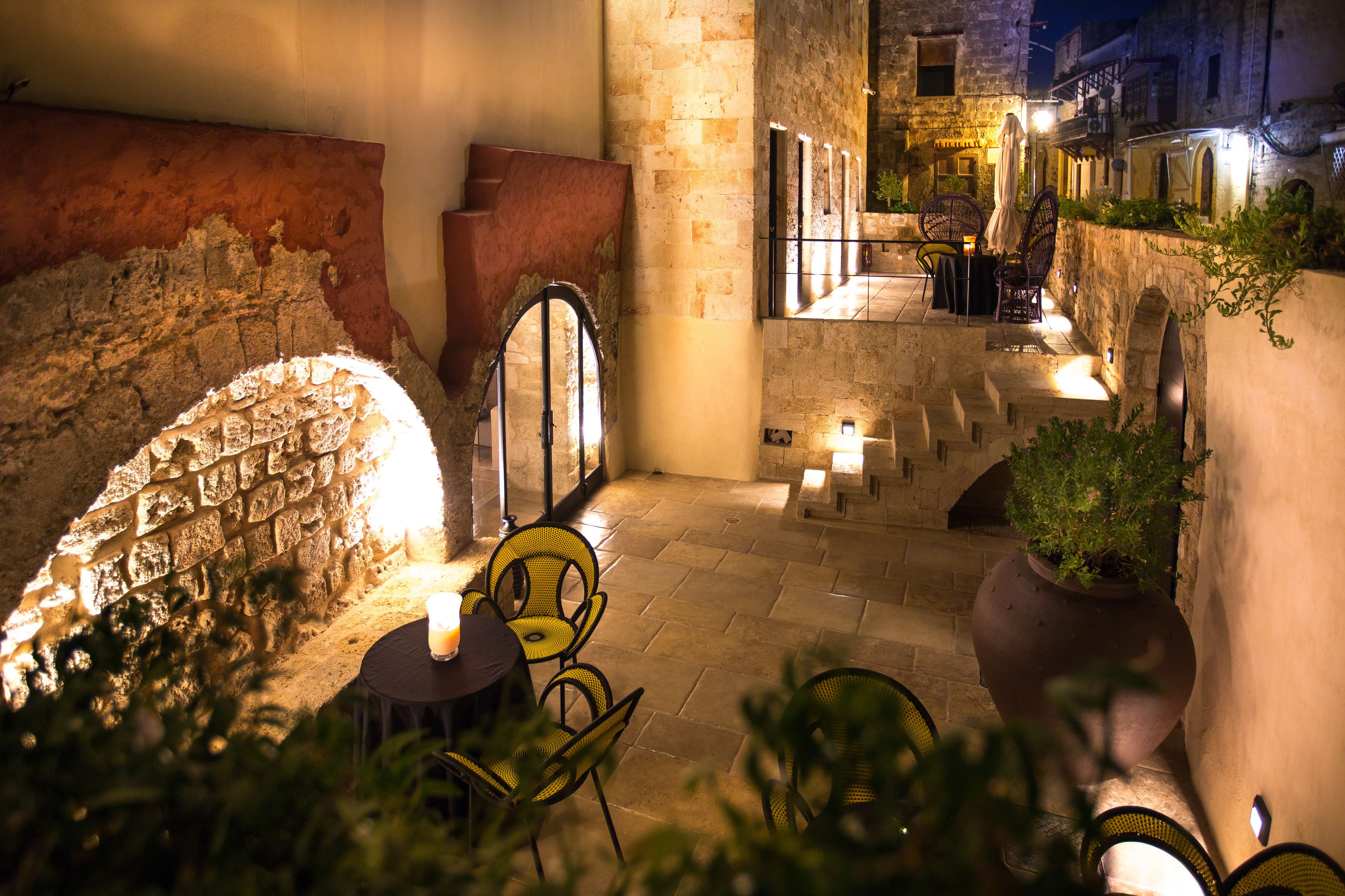 An outdoor patio area with stone walls, a table with chairs, and a potted plant.