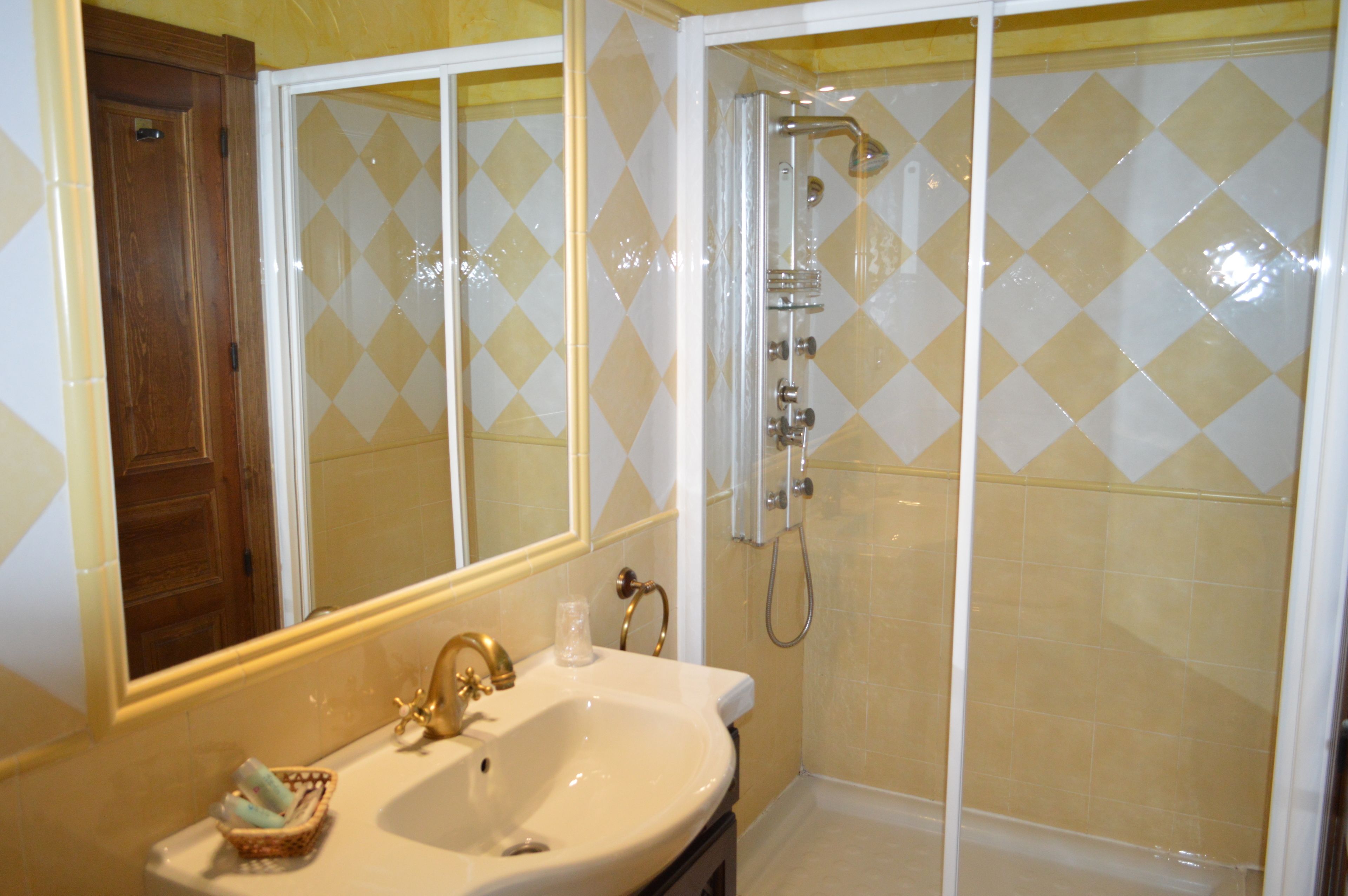 A bathroom with a sink, mirror, and shower.