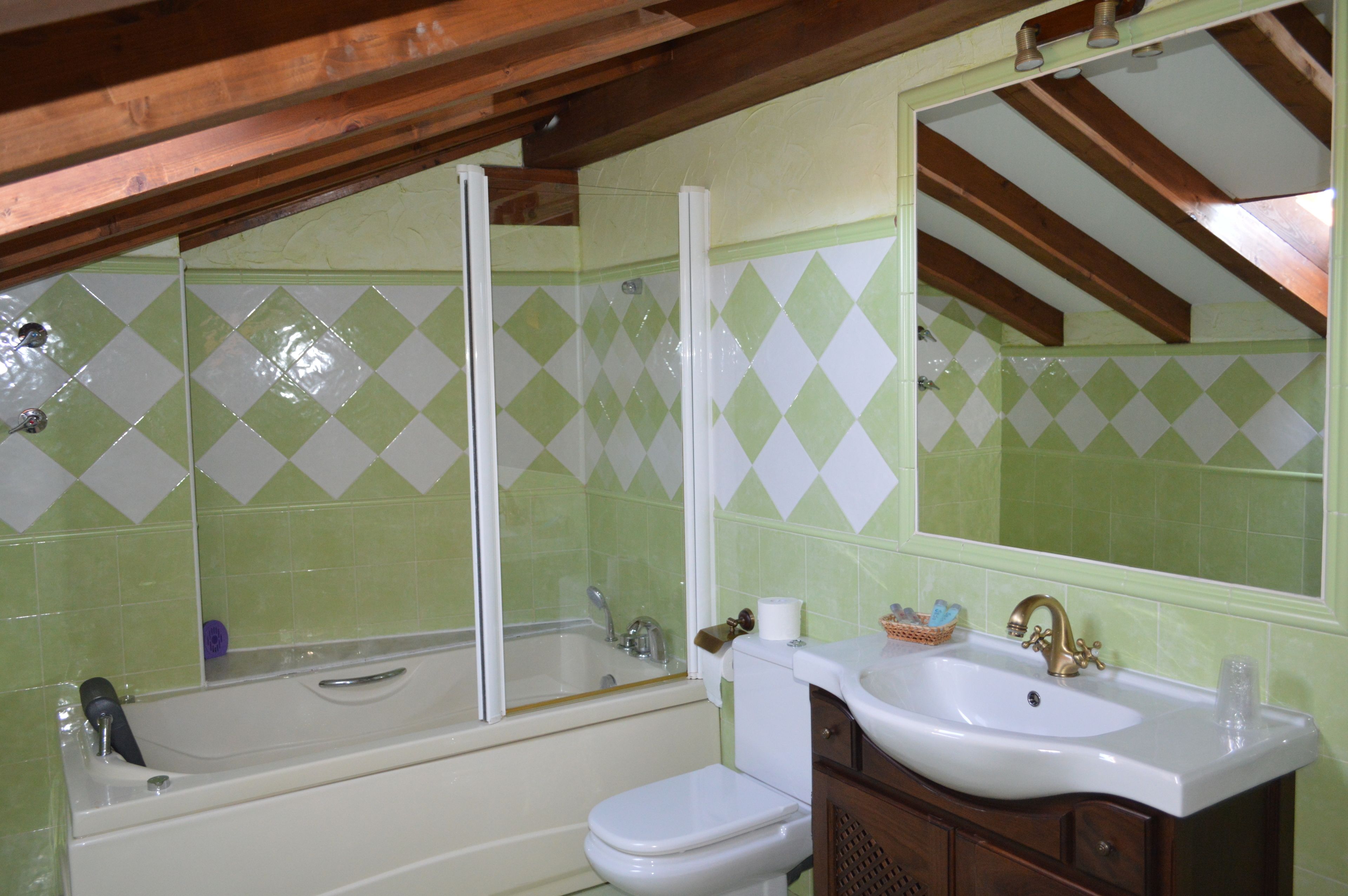 A bathroom with a bathtub, toilet, sink, and a large mirror.