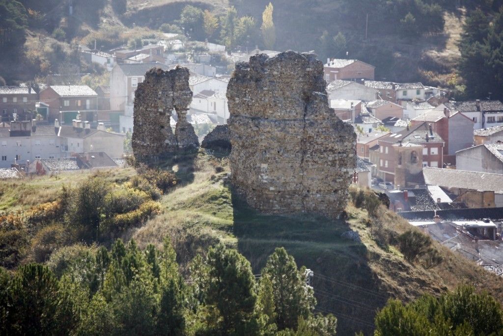 Ruina de piedra histórica con vistas a un pueblo al fondo.