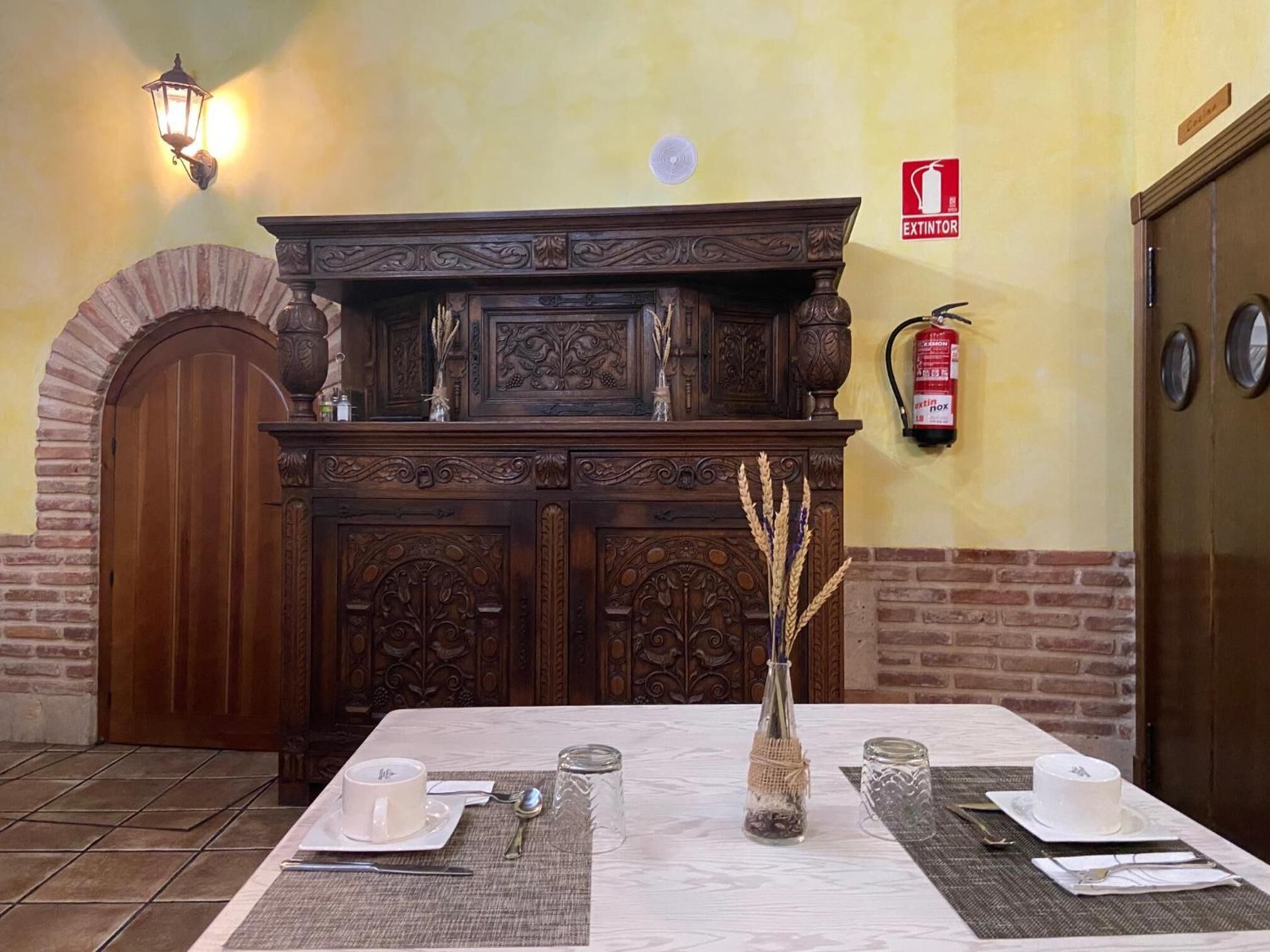 A dining area with a wooden buffet, a fire extinguisher, and a door.