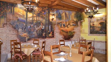 Un restaurante con paredes de ladrillo, mesas de madera y candelabros colgantes.