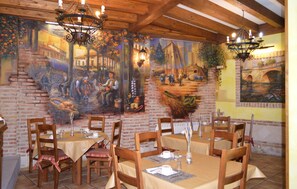 Un restaurante con paredes de ladrillo, mesas de madera y candelabros colgantes.