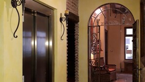 Un pasillo con piso de baldosas, una chimenea de ladrillo y una reja de hierro que da a una zona de estar.