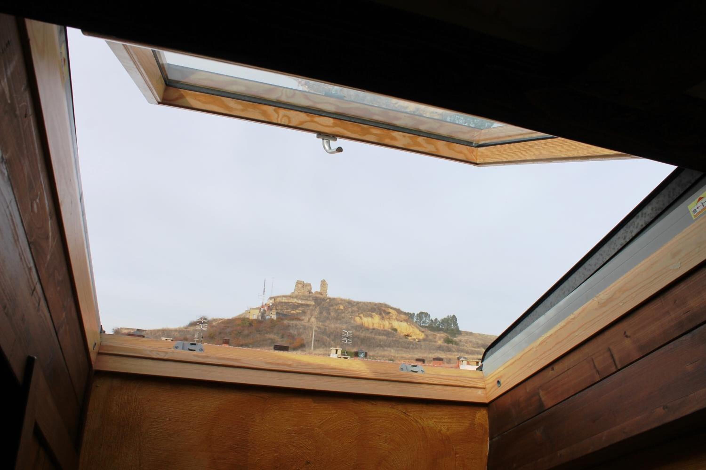 A skylight with a view of a hill and a castle-like structure.