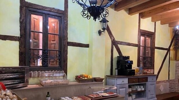Una barra de desayuno con una máquina de café, fruta y bollería.