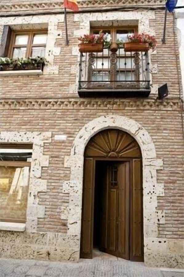A building with a stone facade, a wooden door, and a window with a balcony.