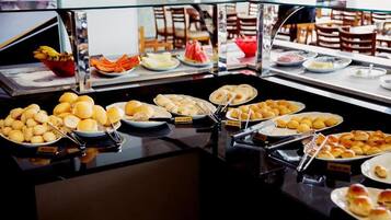 A buffet with various food items including bread, pastries, and fruits.