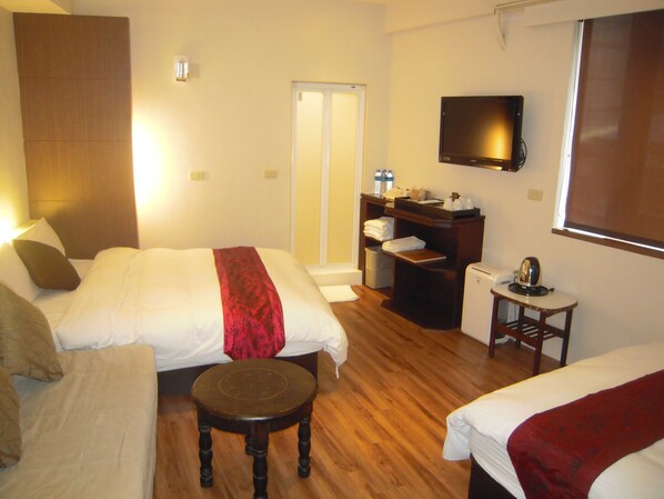 A hotel room with two beds, a small table, a TV, and a wardrobe.