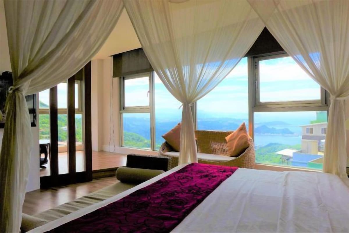 Een slaapkamer met een groot bed, uitzicht op het landschap en een balkon.