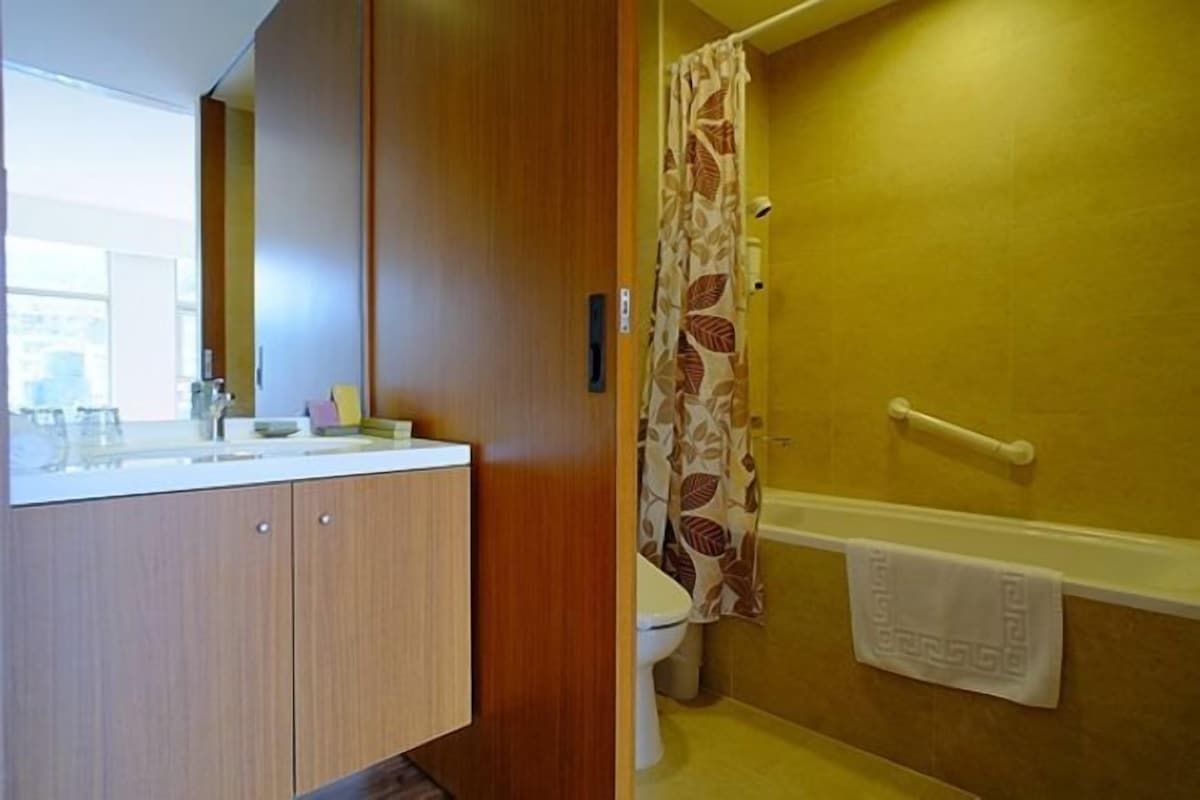 Une salle de bain avec un meuble-lavabo en bois, des toilettes et un rideau de douche.