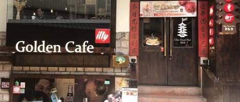 L'esterno del Golden Cafe, con un cartello ben visibile, una grande vetrina e una scalinata che conduce all'ingresso.