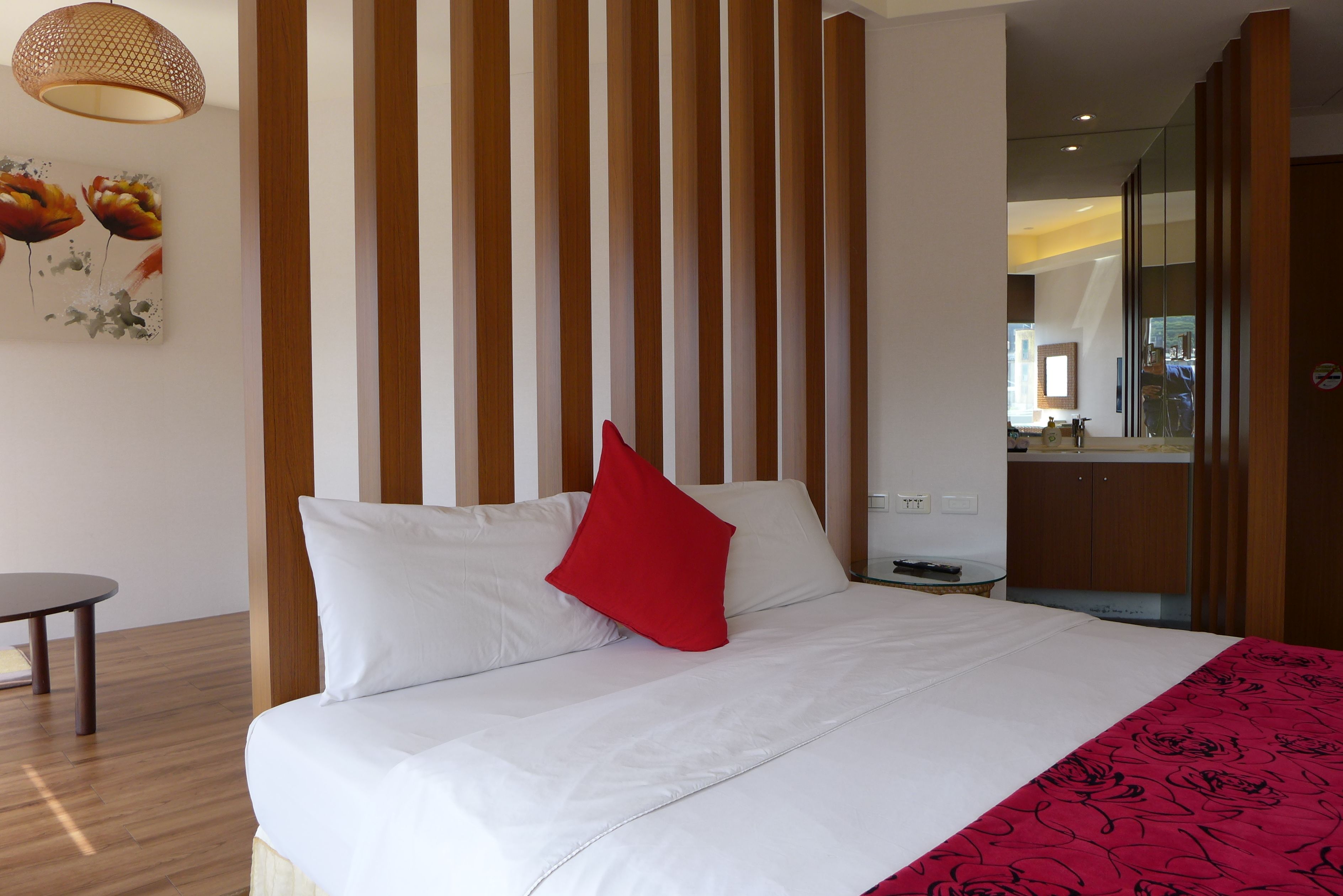 Ein Hotelzimmer mit einem großen Bett, Holzboden, einem kleinen Tisch und einem Bild an der Wand.