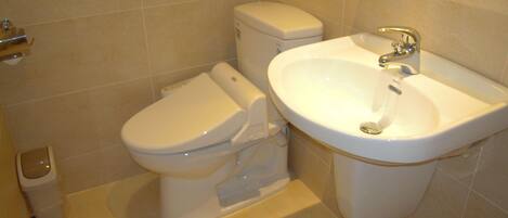 A bathroom with a toilet, a sink, and a trash bin.