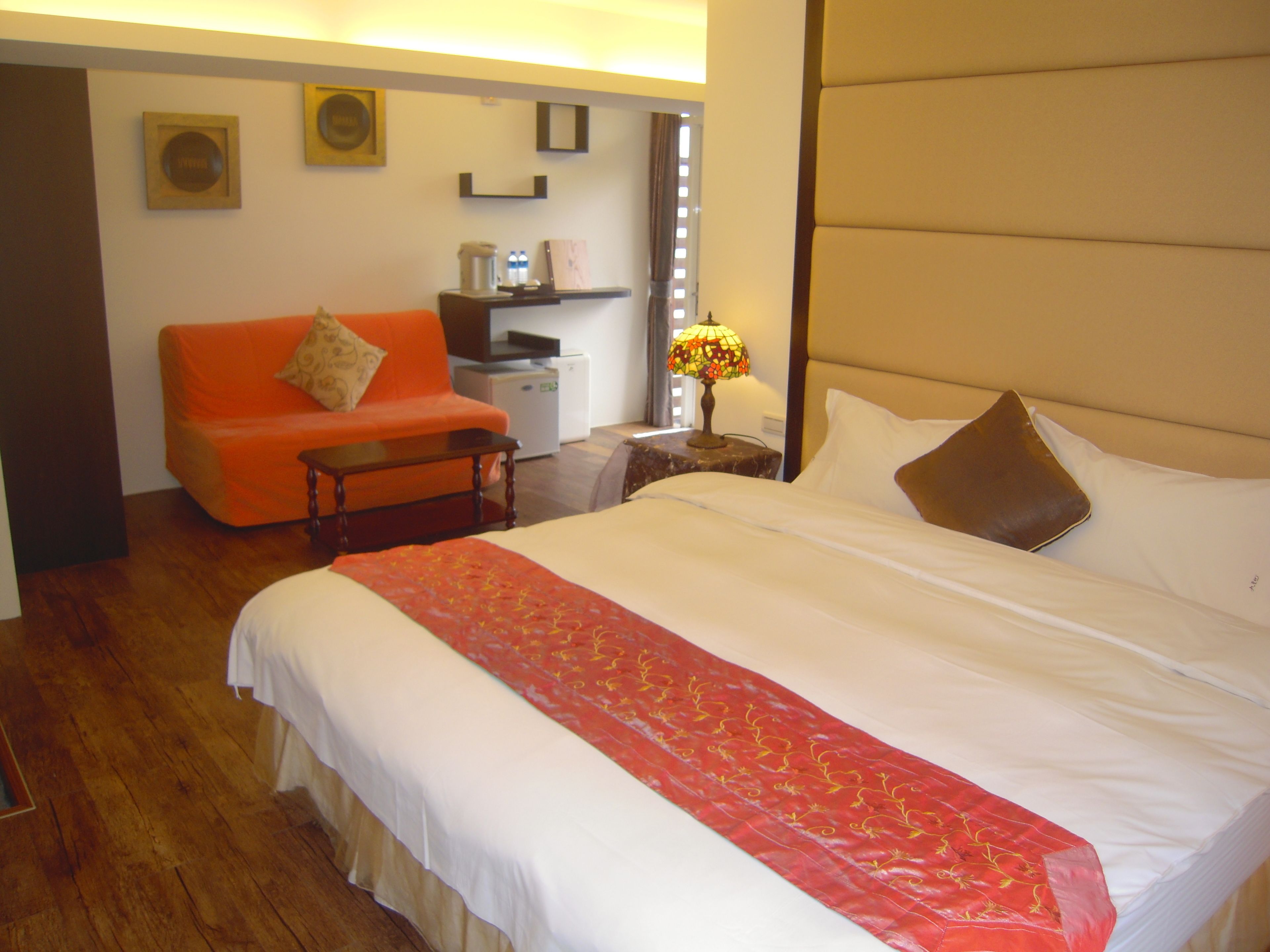 A hotel room with a bed, a sofa, a desk, and a lamp.
