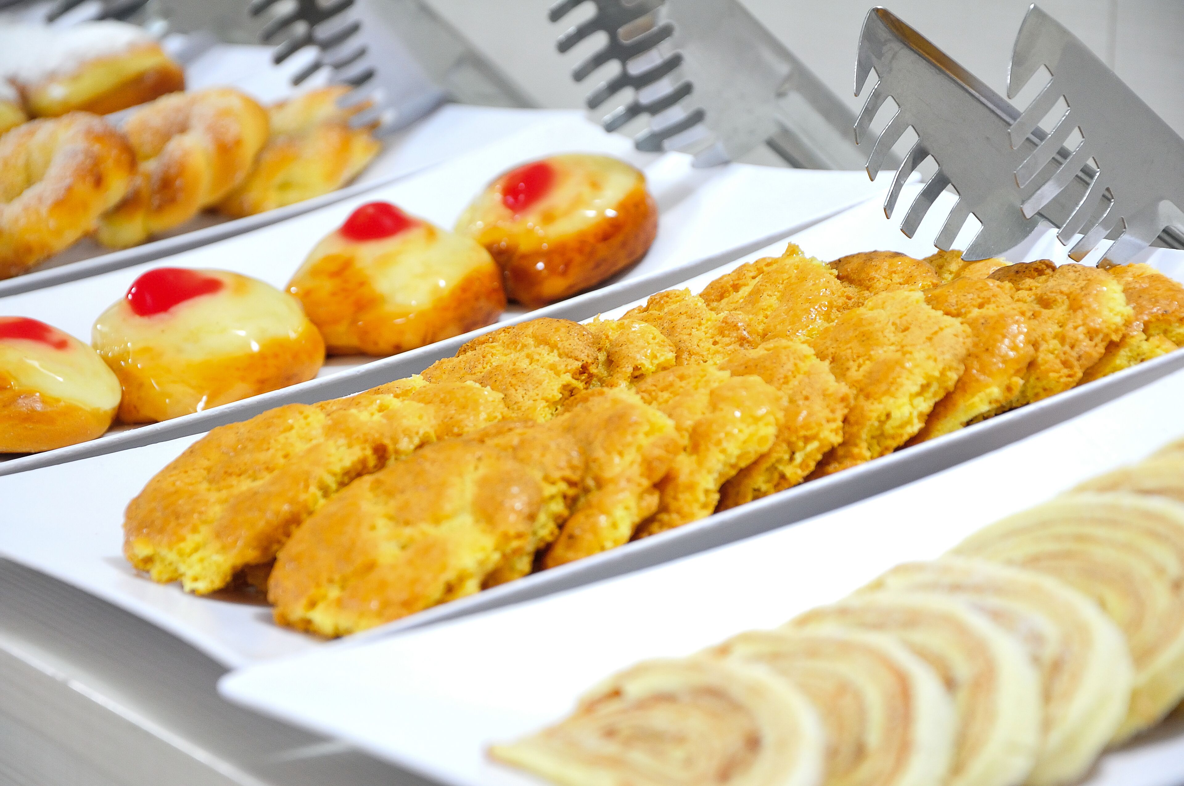 Un bufé con diversas opciones de panadería, incluyendo pasteles y pan.