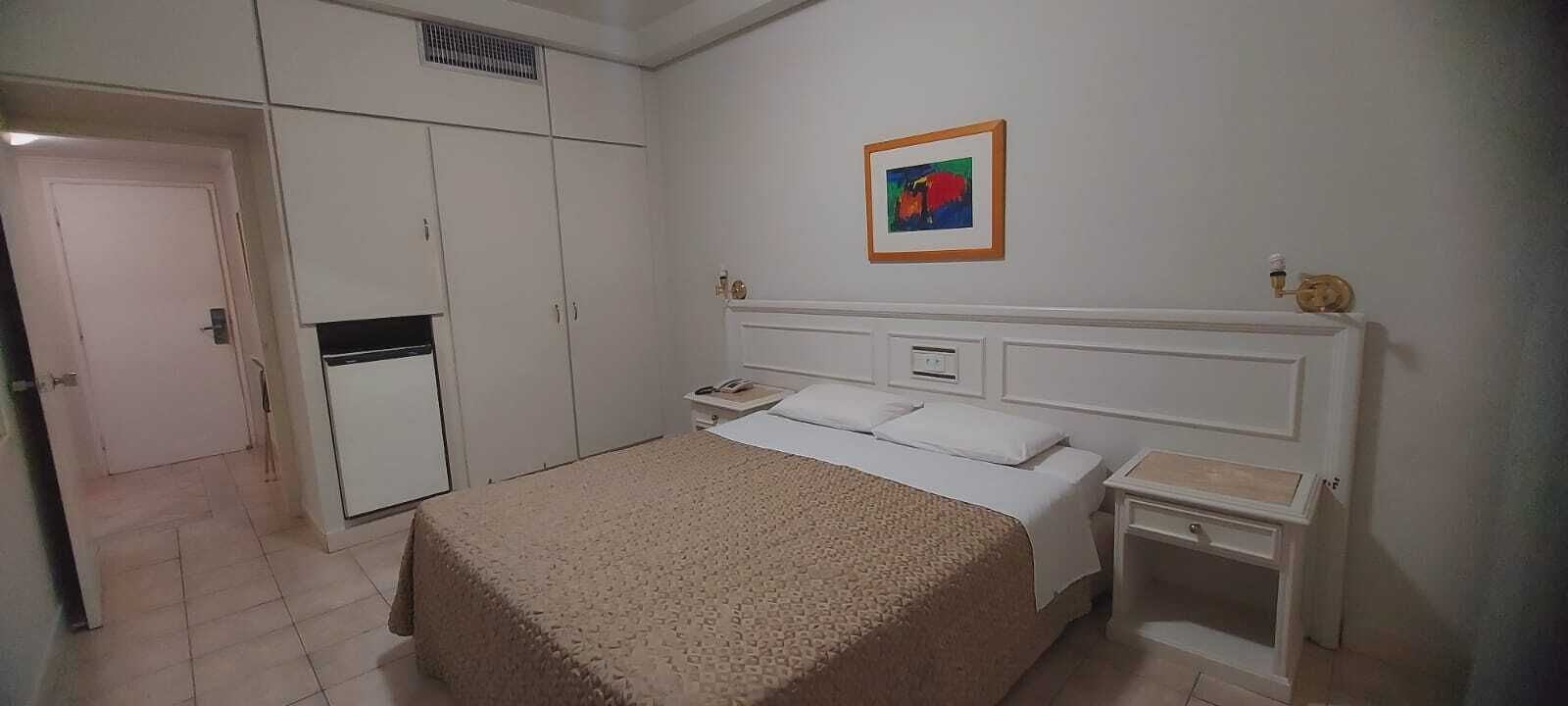 A bedroom with a bed, a wardrobe, and a nightstand.