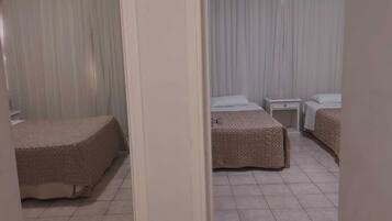 Une chambre d’hôtel avec deux lits, une petite table de chevet et un rideau.