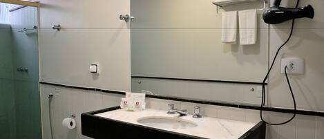 Un baño con lavamanos, espejo, toallero y secador de pelo.